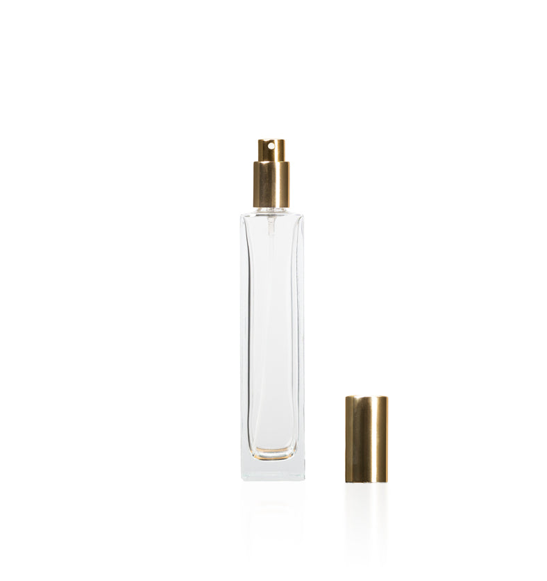 Image of a tall, narrow, clear glass bottle with a gold top on a white background to represent Village Craft & Candle's 4oz Charisma Bottle for room sprays