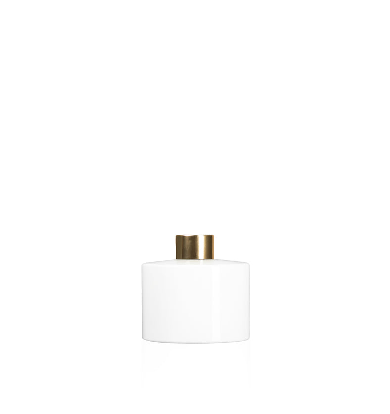Image of a stout white glass diffuser bottle with a gold collar on a white background to represent Village Craft & Candle's Lavish Diffuser Bottle. || Image d'une bouteille de diffuseur en verre blanc trapue avec un col doré sur un fond blanc pour représenter la bouteille de diffuseur Lavish de Village Craft & Candle.