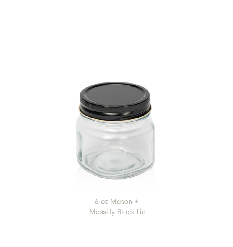 Un pot Mason transparent de 6 oz avec un couvercle noir Massilly sur fond blanc.