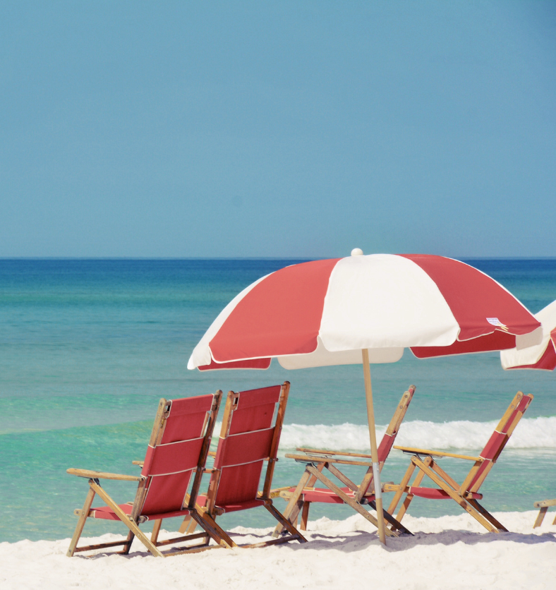 Beach chairs and umbrellas with blue ocean and sandy beach as visual representation of Beach Day Fragrance Oil at Village Craft and Candle || Chaises de plage et parasols avec l'océan bleu et une plage de sable comme représentation visuelle de l'huile parfumée Journée à la Plage chez Village Craft and Candle.