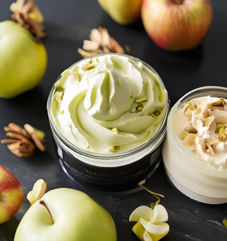 Image of red & green apples around a jar of pistachio creme to represent Village Craft & Candle's Black Vanilla & Oud Fragrance Oil | Image de pommes rouges et vertes autour d'un pot de crème de pistache pour représenter l'huile parfumée Vanille Noire & Oud de Village Craft & Candle