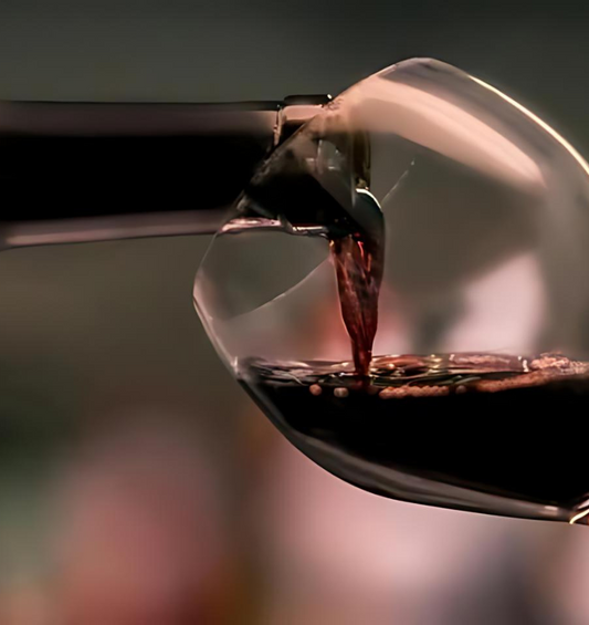 Gros plan de vin rouge versé dans un verre à vin comme représentation visuelle de l'huile parfumée Cabernet disponible chez Village Craft and Candle