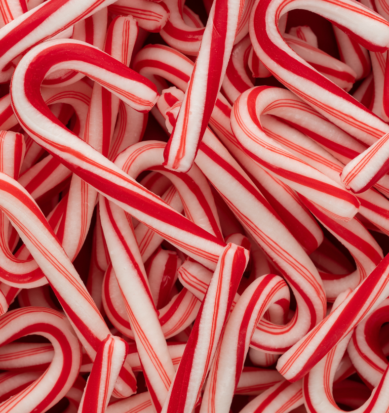 Close up of a pile of minature candy canes as a visual representation of Candy Cane Fragrance Oil available at Village Craft and Candle || Gros plan d'un tas de cannes de bonbon miniatures comme représentation visuelle de l'huile parfumée de canne en bonbon disponible chez Village Craft and Candle
