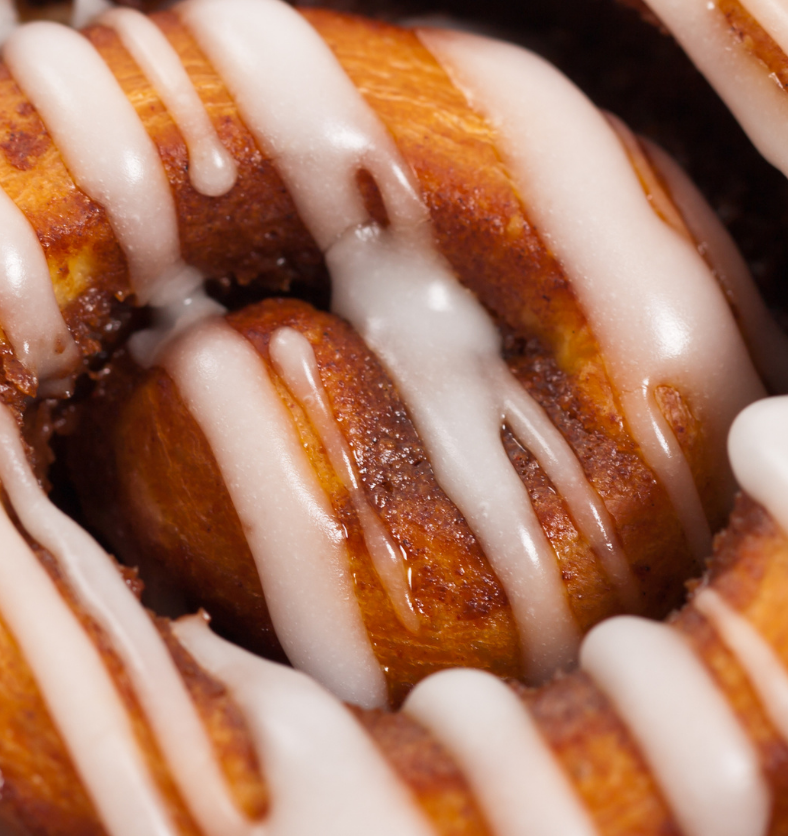 Close up of a cinnamon bun with icing as a visual representation of Cinnamon Bun Fragrance Oil available at Village Craft and Candle || Gros plan d'une brioche à la cannelle avec glaçage comme représentation visuelle de l'huile parfumée à la cannelle disponible chez Village Craft and Candle