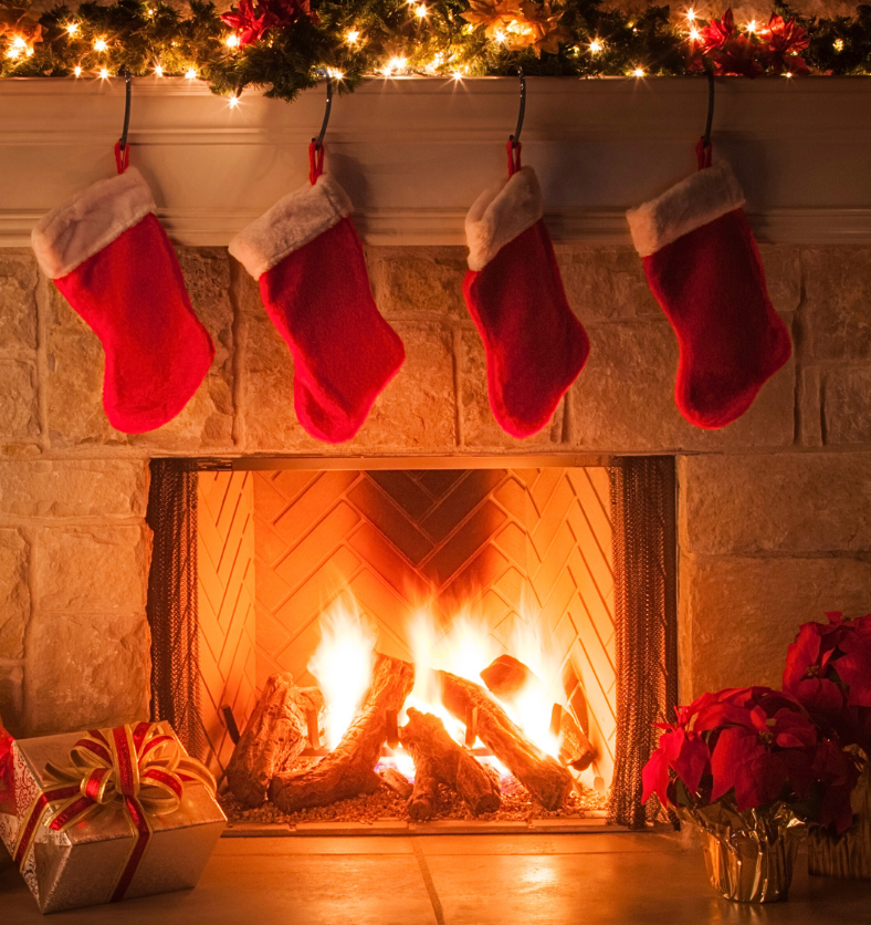 Indoor fireplace with four stockings hanging above it as a visual representation of Holiday Nostalgia Fragrance Oil available at Village Craft and Candle || Cheminée intérieure avec quatre bas suspendus au-dessus comme représentation visuelle de l'huile parfumée Holiday Nostalgia disponible chez Village Craft and Candle.