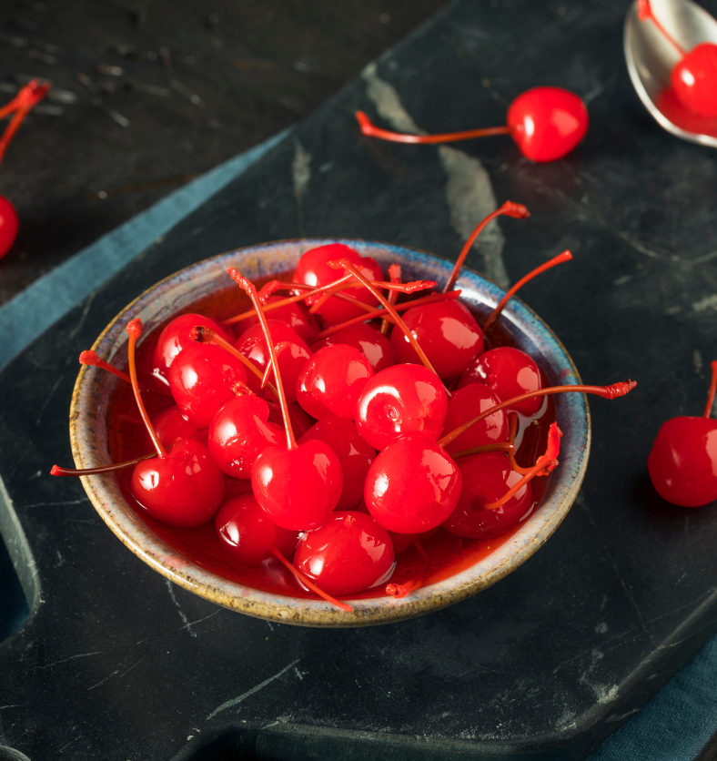 A bowl of marashino cherries on a black marble cutting board as a visual representation of Maraschino Cherry Fragrance Oil available at Village Craft and Candle || Un bol de cerises au marasquin sur une planche à découper en marbre noir comme représentation visuelle de l'huile parfumée de cerise au marasquin disponible chez Village Craft and Candle