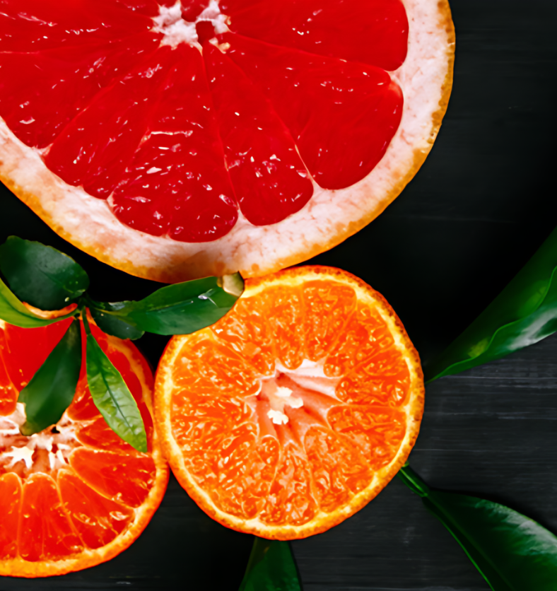 A grapefruit, mandarin, and orange on a black wood table as a visual representation of Satsuma Mandarin Fragrance Oil available at Village Craft and Candle || Un pamplemousse, une mandarine et une orange sur une table en bois noir comme représentation visuelle de l'huile parfumée Satsuma Mandarin disponible chez Village Craft and Candle