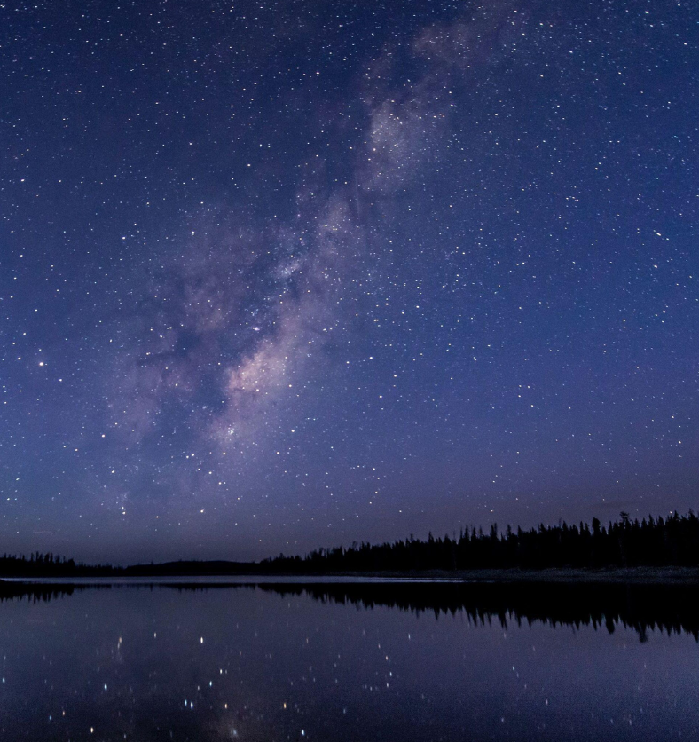 Starry night sky above a perfectly reflective lake with trees in the background as a visual representation of Silent Night Fragrance Oil available at Village Craft and Candle || Ciel étoilé au-dessus d'un lac parfaitement réfléchissant avec des arbres en arrière-plan comme représentation visuelle de l'huile parfumée Silent Night disponible chez Village Craft and Candle