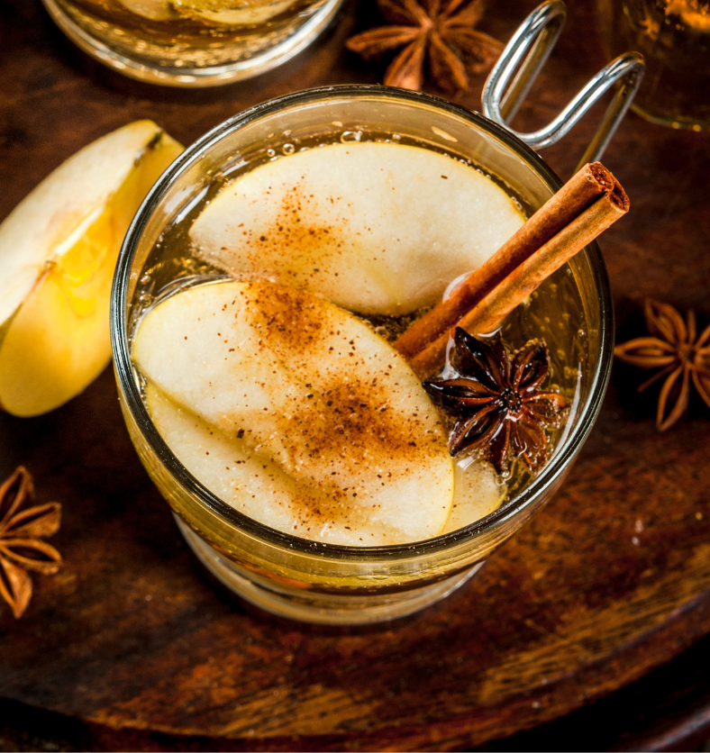 Glass of apple cider with cinnamon and pears as a visual representation of Spiced Apple Cider Fragrance Oil available at Village Craft and Candle || Verre de cidre de pomme avec cannelle et poires comme représentation visuelle de l'huile parfumée au cidre de pomme épicé disponible chez Village Craft and Candle