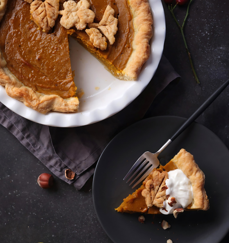 Sliced pumpkin pie with whipped cream and cinnamon as a visual representation of Spiced Pumpkin Pie Fragrance Oil available at Village Craft and Candle || Tarte à la citrouille en tranches avec crème fouettée et cannelle comme représentation visuelle de l'huile parfumée pour tarte à la citrouille épicée disponible chez Village Craft and Candle