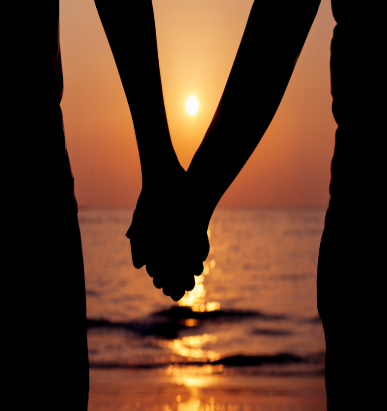 Couple holding hands in front of an ocean sunset as a visual representation of Love Spell Fragrance Oil available at Village Craft and Candle || Couple se tenant la main devant un coucher de soleil sur l'océan comme représentation visuelle de l'huile parfumée Love Spell disponible chez Village Craft and Candle