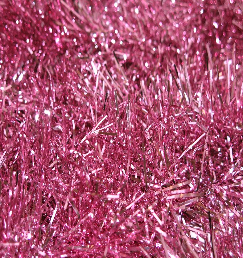 Ultra close up of a bed of shiny pink tinsel as a visual representation of Pink Tinsel Fragrance Oil available at Village Craft and Candle || Ultra gros plan d'un lit de guirlandes roses brillantes comme représentation visuelle de l'huile parfumée de guirlandes roses disponible chez Village Craft and Candle
