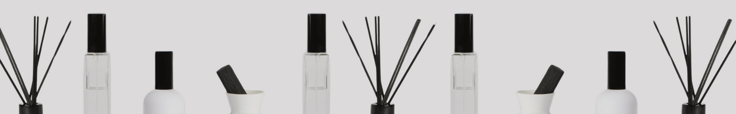 white diffuser and room spray collection with black lids and reeds lined up horizontally against plain backdrop