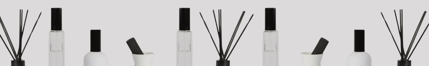 white diffuser and room spray collection with black lids and reeds lined up horizontally against plain backdrop 