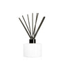 Image of a stout white glass diffuser bottle with a black collar & fiber reeds on a white background to represent Village Craft & Candle's Lavish Diffuser Bottle. || Image d'une bouteille de diffuseur en verre blanc trapue avec un col noir et des tiges en fibre sur fond blanc pour représenter la bouteille de diffuseur Lavish de Village Craft & Candle.