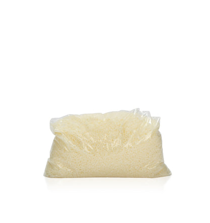 Image of white beads of wax in a clear bag to represent Village Craft & Candles White Beeswax Pastilles. || Image de perles de cire blanche dans un sac transparent pour représenter les pastilles de cire blanche de Village Craft & Candles.