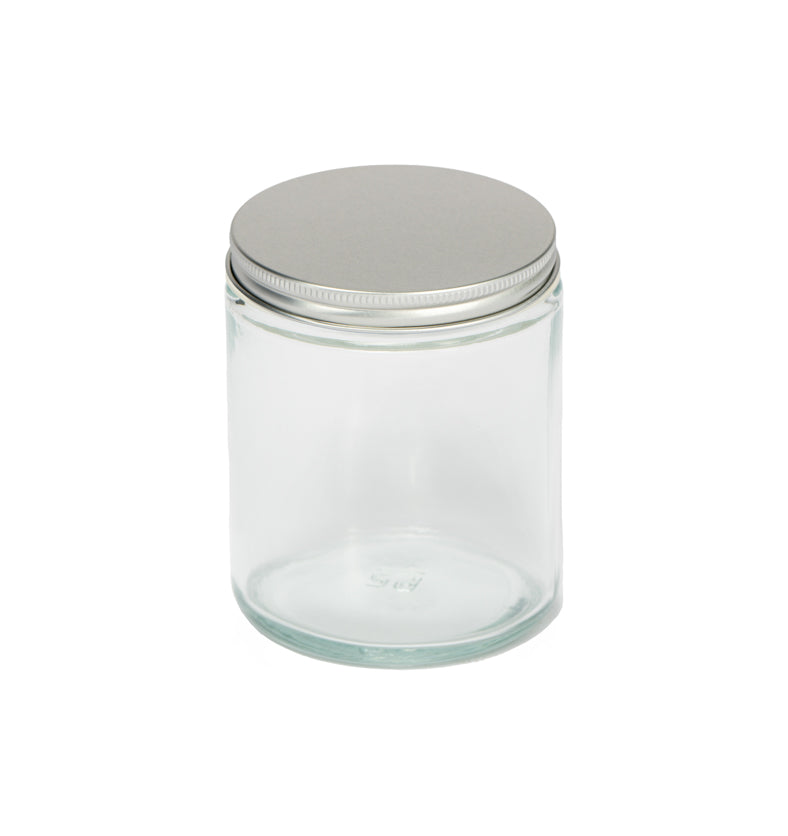 Image of a clear glass jar with a low profile silver lid to represent Village Craft & Candle's 8oz Clear Flint Element Straight Side Jar & Silver Element Lid for candle making || Image d'un pot en verre transparent avec un couvercle argenté à profil bas représentant le pot droit Element Flint clair de 8 oz et le couvercle argenté Element de Village Craft & Candle pour la fabrication de bougies.