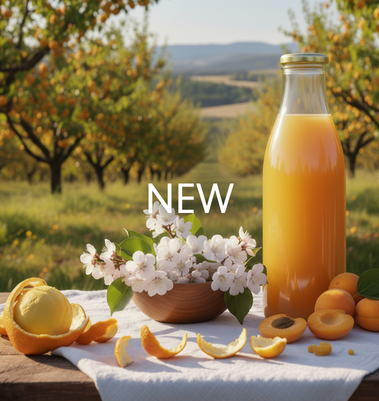 Apricot Nectar Fragrance Oil visual, showing a bottle of golden apricot juice, fresh apricot halves, and white blossoms on a table in an orchard. 