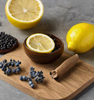 Lemon, cinnamon, and blueberries on a wood cutting board as a visual representation of Agar Wood EmotiScents (Energy) Fragrance Oil available at Village Craft and Candle || Citron, cannelle et myrtilles sur une planche à découper en bois comme représentation visuelle de l'huile parfumée Agar Wood EmotiScents (Energy) disponible chez Village Craft and Candle