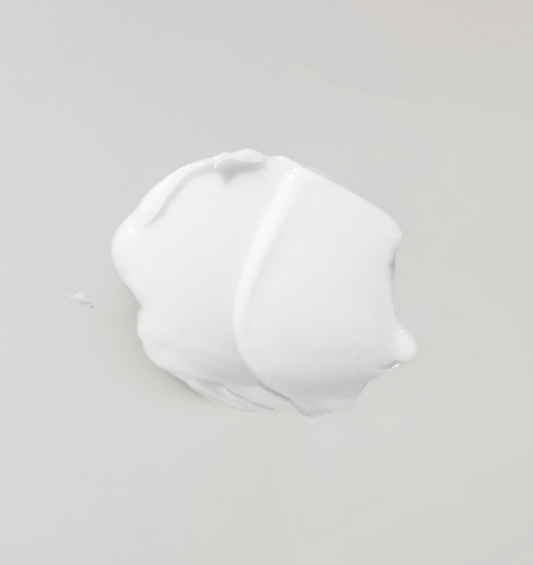  Lotion corporelle blanche sur un fond gris pâle.