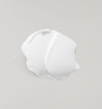 White body lotion on a light grey background. || Lotion corporelle blanche sur un fond gris pâle.