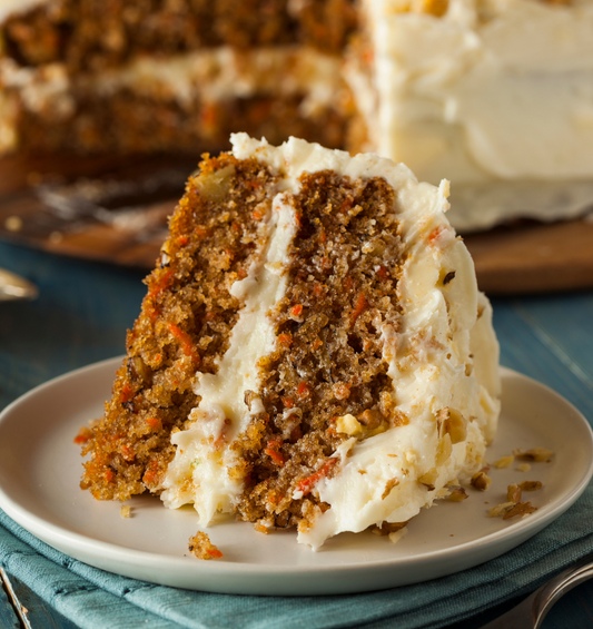 Small piece of carrot cake with cream cheese icing and a bite missing as a visual representation of Cream Cheese Carrot Cake Fragrance Oil available at Village Craft and Candle 