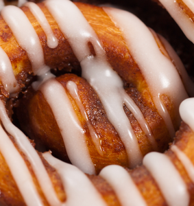 Close up image of a cinnamon bun with icing to represent Cinnamon Bun Fragrance Oil from Village Craft & Candle for candle making. | Image en gros plan d'une brioche à la cannelle avec du glaçage pour représenter l'huile parfumée de brioche à la cannelle de Village Craft & Candle pour la fabrication de bougies.