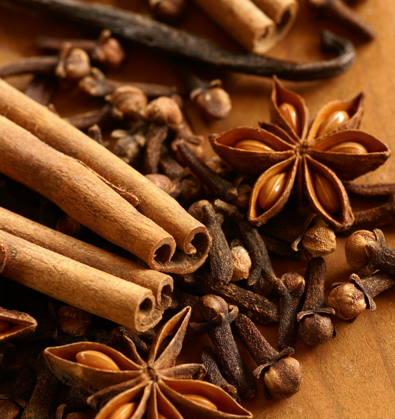 Cinnamon sticks, cloves and star anise as a visual representation of Cinnamon & Spice Fragrance Oil available at Village Craft and Candle || Des bâtons de cannelle sur un lit de piment de la Jamaïque comme représentation visuelle de l'huile parfumée à la cannelle et aux épices disponible chez Village Craft and Candle.