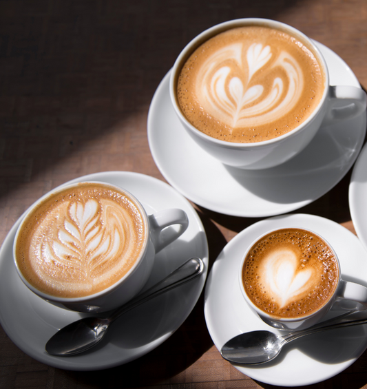  Café au lait au caramel dans une tasse blanche sur une table en bois comme représentation visuelle de l'huile parfumée au café et au caramel disponible chez Village Craft and Candle