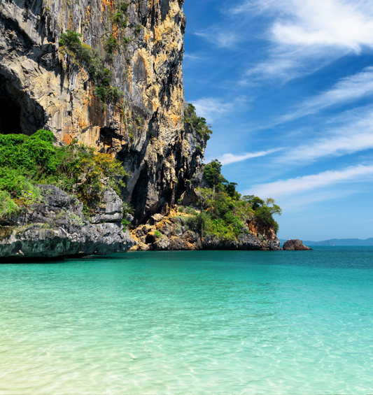 Clear blue ocean with tall rocky landscape background as a visual representation of Emerald Sea Fragrance Oil available at Village Craft and Candle 