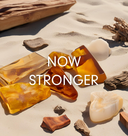  Image de morceaux d'ambre et de bois flotté posés sur le sable pour représenter l'huile parfumée Golden Santal de Village Craft & Candle
