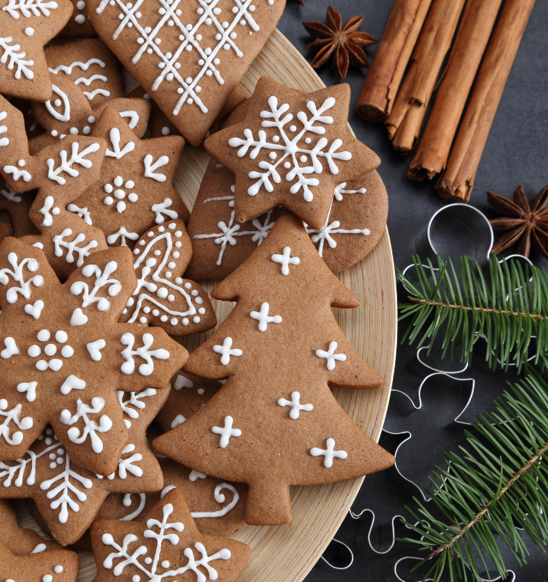 Decoarated gingerbread men next to tied cinnamon sticks as a visual representation of Gingerbread Fragrance Oil available at Village Craft and Candle || Bonhommes en pain d'épice décorés à côté de bâtons de cannelle attachés comme représentation visuelle de l'huile parfumée en pain d'épice disponible chez Village Craft and Candle