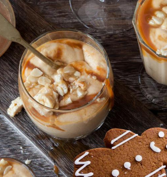 Creamy mousse dessert with carmel sauce topping in a glass sitting beside gingerbread with white icing as a visual representation of Gingerbread Caramel Mousse Fragrance Oil available at Village Craft and Candle 