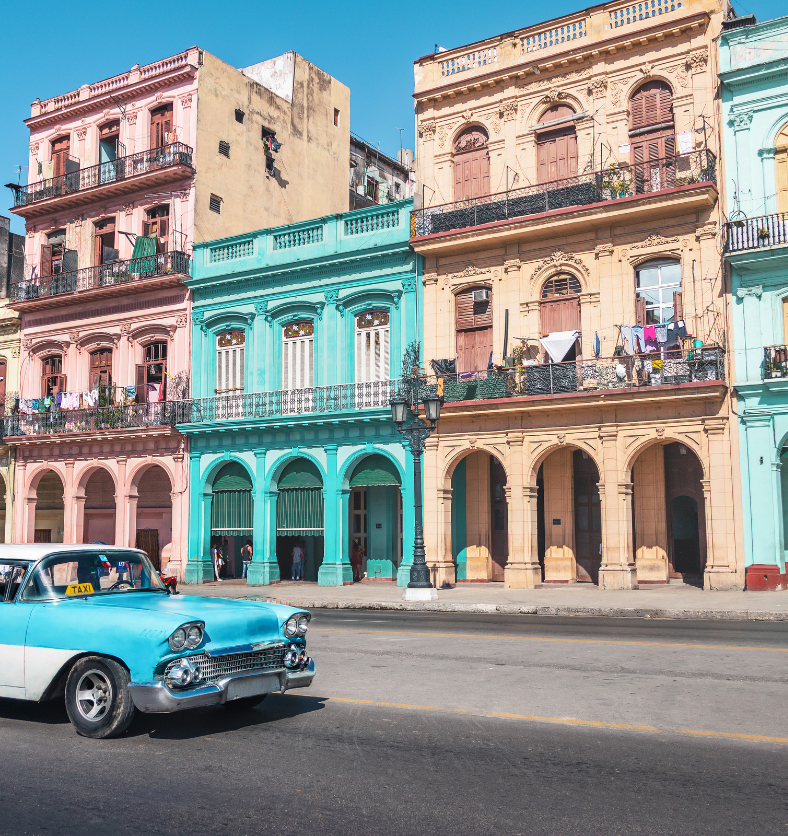 Classic cars of various colours in front of old Cuban buildings as a visual representation of Havana Fragrance Oil available at Village Craft and Candle || Voitures classiques de différentes couleurs devant de vieux bâtiments cubains comme représentation visuelle de l'huile parfumée de La Havane disponible chez Village Craft and Candle