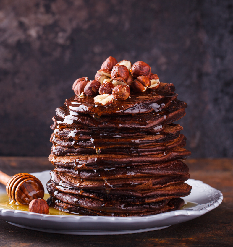 Stack of crepes and pancakes drizzled in honey and chocolate as a visual representation of Maple Syrup & Hazelnut Fragrance Oil available at Village Craft and Candle || Pile de crêpes et de crêpes arrosées de miel et de chocolat comme représentation visuelle de l'huile parfumée au sirop d'érable et aux noisettes disponible chez Village Craft and Candle
