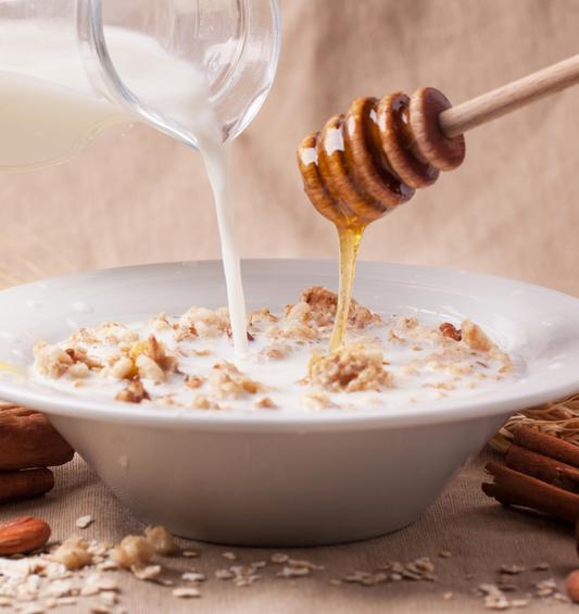 Warm bowl of oatmeal and drizzled honey with milk and cinnamon as a visual representation of Oatmeal and Warm Honey Fragrance at Village Craft & Candle | Un bol chaud de gruau avec un filet de miel, du lait et de la cannelle comme représentation visuelle du parfum Gruau et Miel Chaud de Village Craft & Candle.