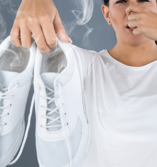 Woman holding stinky white tennis shoes as a visual representation of Odor Eater Fragrance Oil available at Village Craft and Candle 