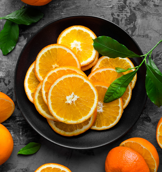  Collection de tranches d'orange sur une assiette noire comme représentation visuelle de l'huile essentielle d'orange de Floride disponible chez Village Craft and Candle