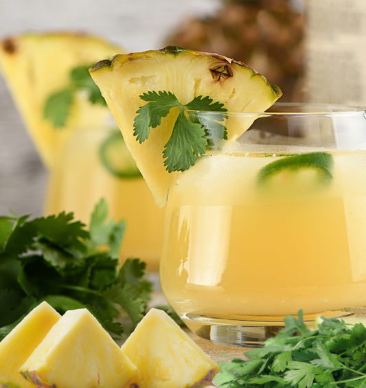 Yellow drink with a pineapple slice & cilantro garnish as a visual representation of Pineapple Cilantro Fragrance Oil available at Village Craft and Candle 