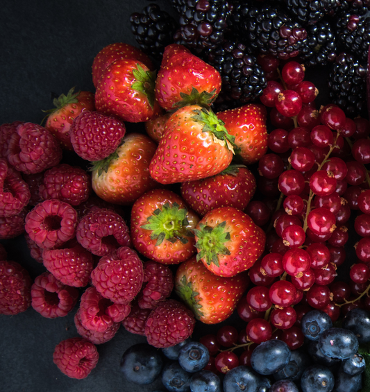 Mixed berries on dark counter as a visual representation of Razzleberry Fragrance Oil available at Village Craft and Candle 