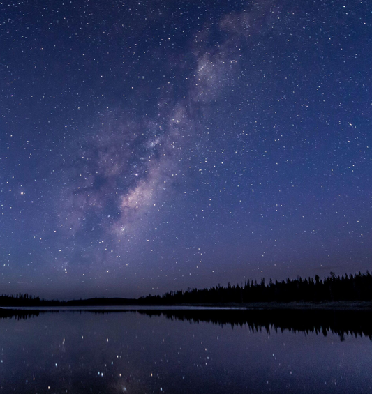 Starry night sky above a perfectly reflective lake with trees in the background as a visual representation of Silent Night Fragrance Oil available at Village Craft and Candle 