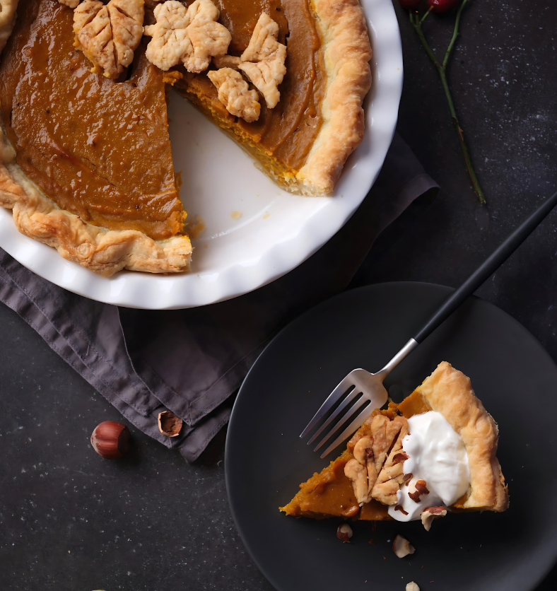 Sliced pumpkin pie with whipped cream and cinnamon  as a visual representation of Spiced Pumpkin Pie Fragrance Oil available at Village Craft and Candle || Tarte à la citrouille en tranches avec crème fouettée et cannelle comme représentation visuelle de l'huile parfumée pour tarte à la citrouille épicée disponible chez Village Craft and Candle