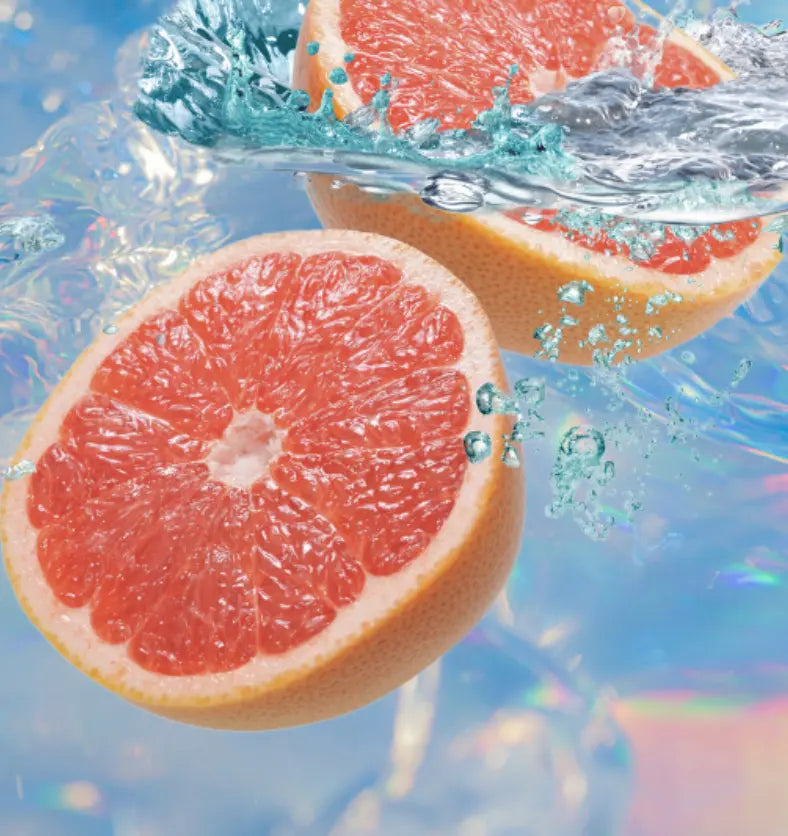 Grapefruits underneath a blue and pink shimmering pool as a visual representation of Uplifting Essential Oil Blend available at Village Craft and Candle || Pamplemousses sous une piscine scintillante bleue et rose comme représentation visuelle du mélange d'huiles essentielles édifiant disponible chez Village Craft and Candle