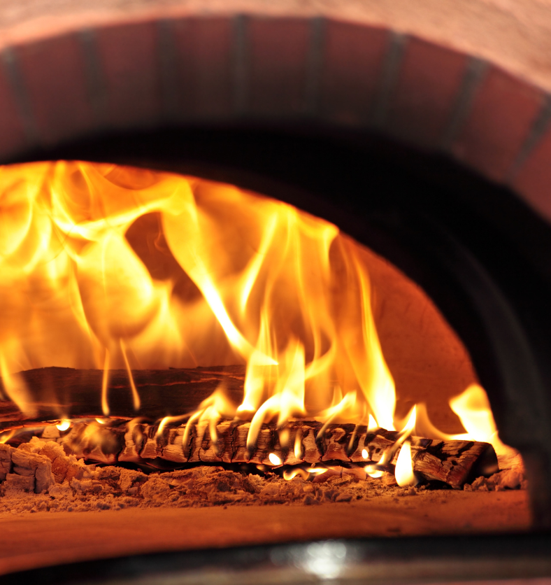 Looking through a wood stove to see the fire inside as a visual representation of Wood Smoke Fragrance Oil available at Village Craft and Candle || En regardant à travers un poêle à bois pour voir le feu à l'intérieur comme une représentation visuelle de l'huile parfumée de fumée de bois disponible chez Village Craft and Candle