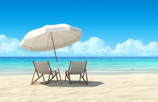 Two beach chairs on white sand beach under an umbrella as a visual representation of All Summer Long Fragrance Oil available at Village Craft and Candle 