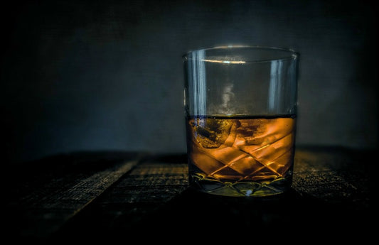  Verre de bourbon dans le noir comme représentation visuelle de l'huile parfumée de bourbon disponible chez Village Craft and Candle