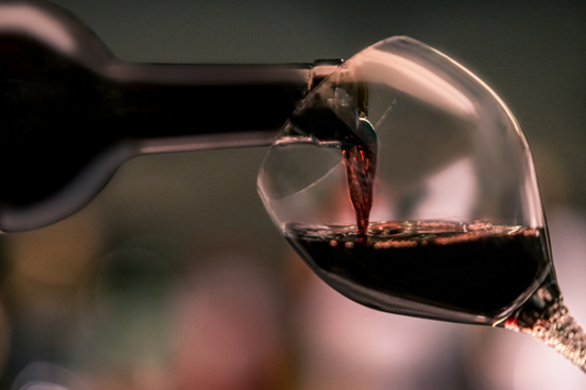  Gros plan de vin rouge versé dans un verre à vin comme représentation visuelle de l'huile parfumée Cabernet disponible chez Village Craft and Candle