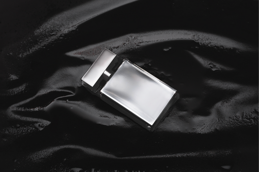 Silver cologne bottle laying on black background as a visual representation of Oud & Woods Fragrance Oil available at Village Craft and Candle 