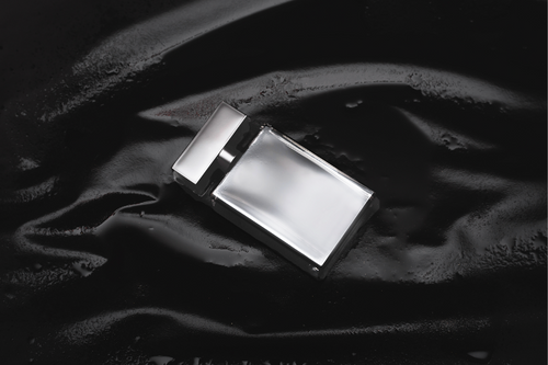 Silver cologne bottle laying on black background || Bouteille de cologne argentée portant sur fond noir