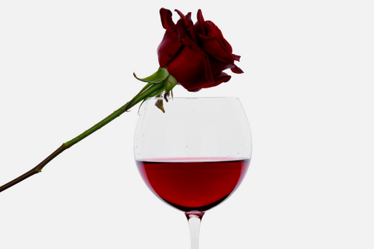  Verre de vin rouge avec une rose posée dessus comme représentation visuelle de l'huile parfumée de vin rouge et de roses disponible chez Village Craft and Candle